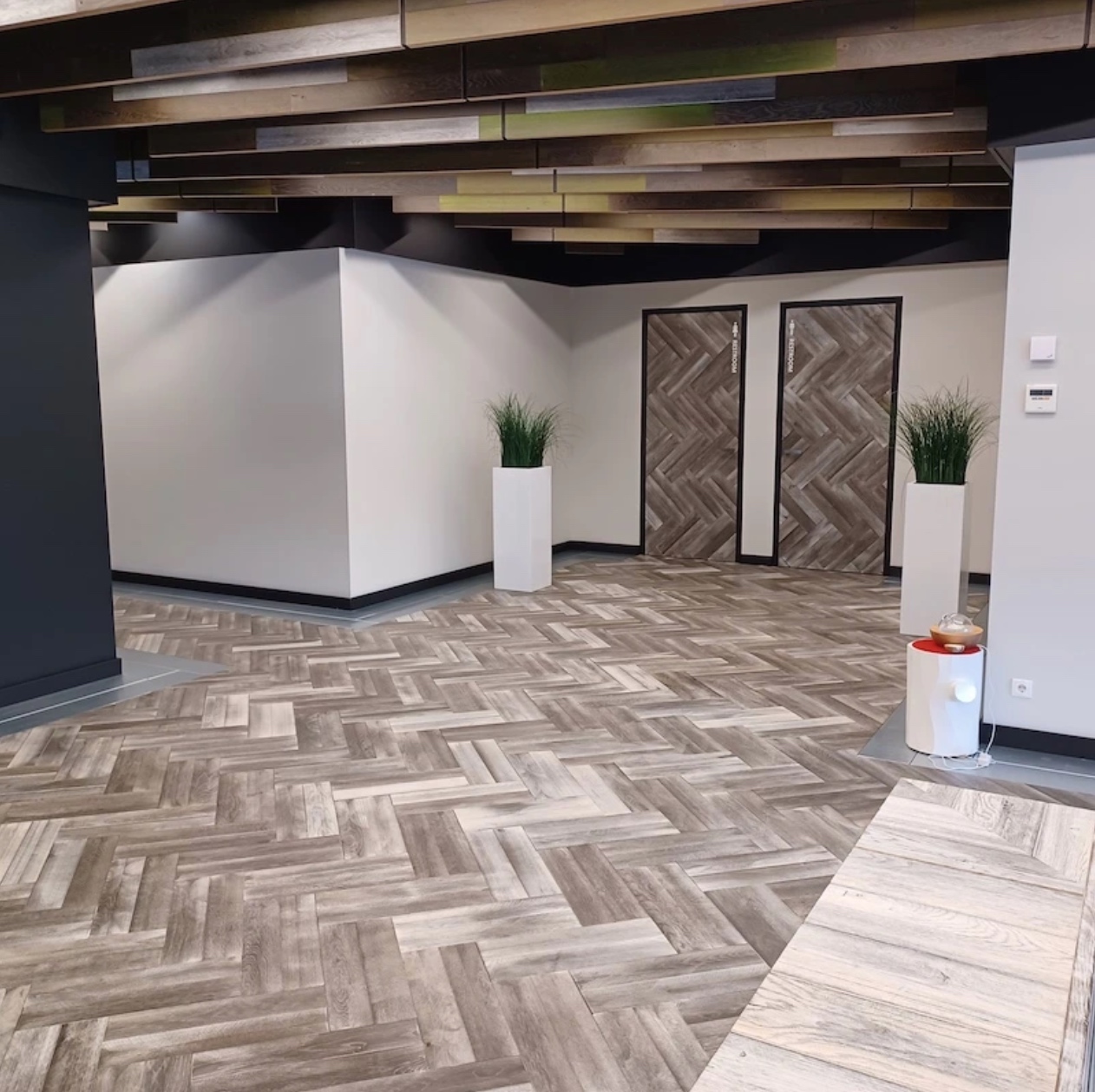 Dubové parkety Košice – Dvere z dubových parkiet v rovnakom dekore ako sivobiela vinylová podlaha herringbone – čistý a moderný interiér od ParkettWorld Košice.